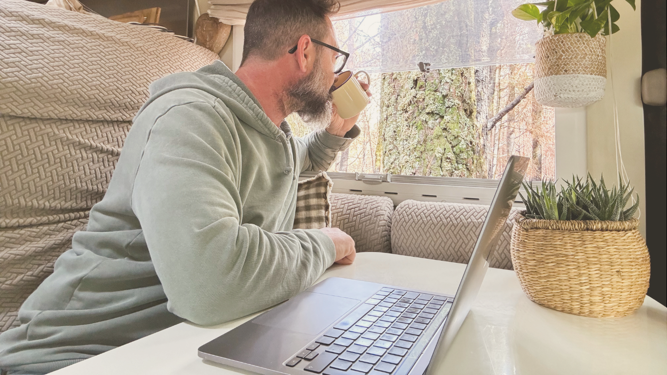 A digital nomad man working on a laptop inside his camper van, showcasing remote work and van life travel.